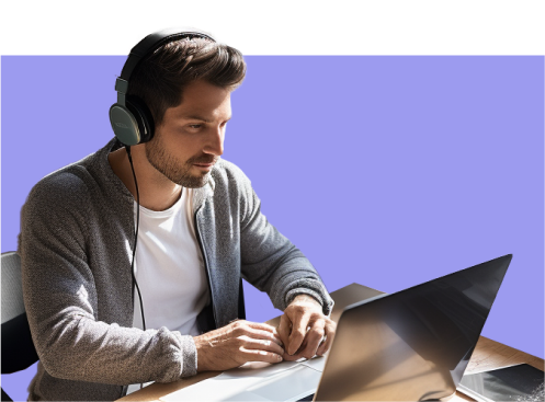 Imagem de um homem branco de cabelos escuros, olhando para seu notebook. Ele usa fone de ouvido, uma camiseta branca e um moletom cinza.